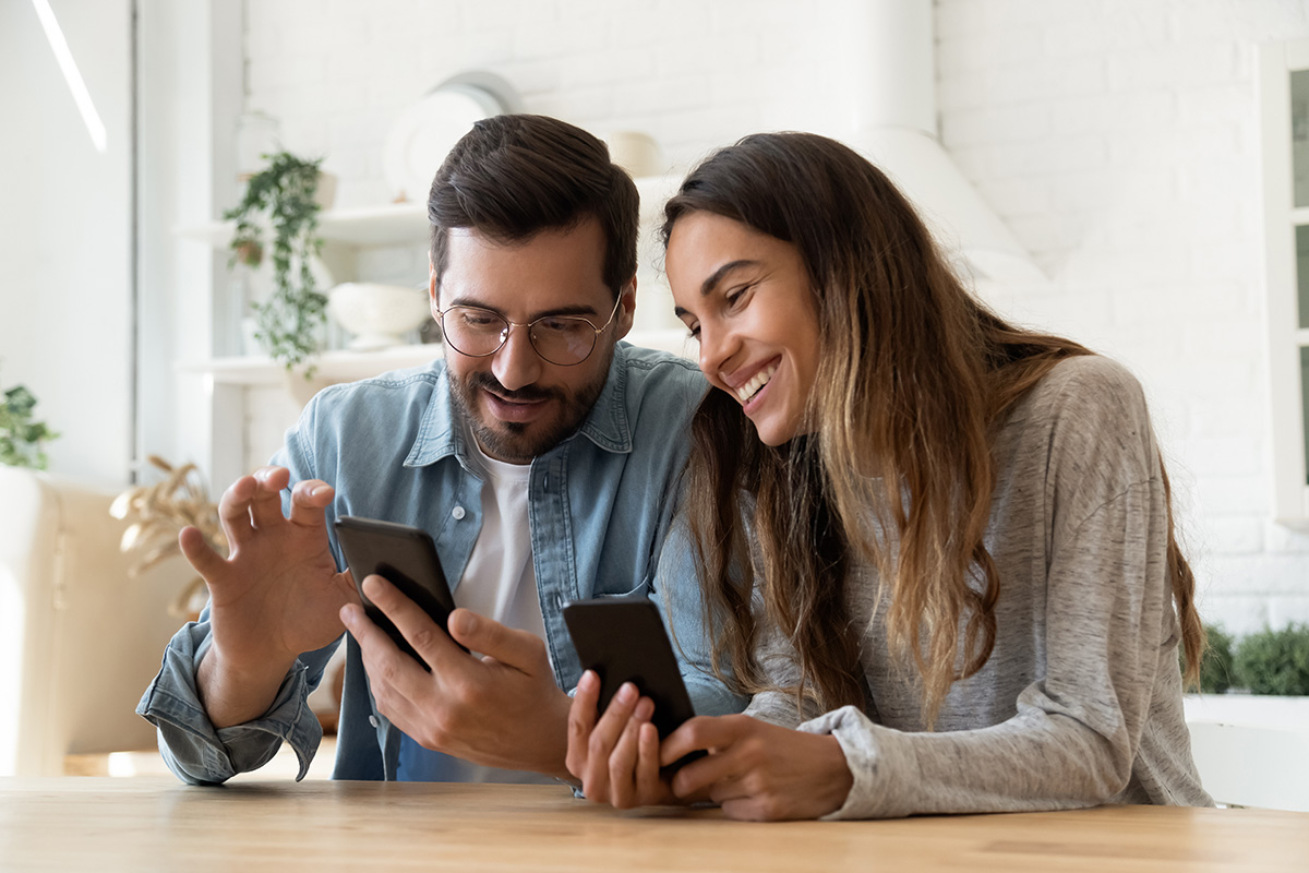 Hombre y mujer sonriendo mientras miran el movil
